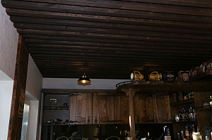 Отделка потолка фальшбалками из хвои для домашнего бара в стиле шале